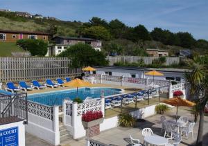 a swimming pool with chairs and tables and umbrellas at Pool and Valley View in Mawgan Porth