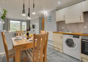 a kitchen and dining room with a table and a washing machine at Pool and Valley View in Mawgan Porth