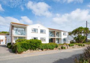 a white apartment building with bushes and trees at Pool and Valley View in Mawgan Porth