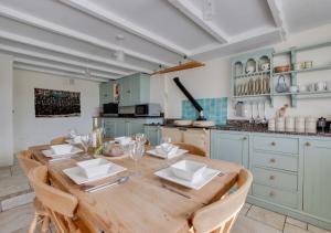a dining room with a wooden table and a kitchen at Stargazy in Mousehole