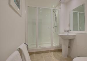 a white bathroom with a shower and a sink at Quayside in Porthleven