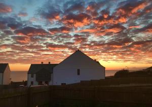 un tramonto su una casa bianca e una recinzione di Sea Breezes a Porthleven