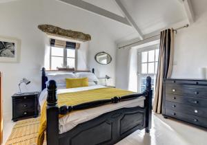 a bedroom with a black and yellow bed and windows at The Byre - Sennen in Sennen