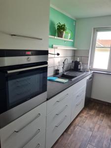 a kitchen with white cabinets and a black stove top oven at Bergliebe - Talstation in Blaichach