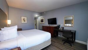 ein Hotelzimmer mit einem Bett und einem Schreibtisch mit einem TV in der Unterkunft SeaSide Inn & Suites in Santa Cruz
