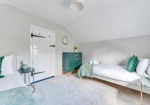Kettleburgh的住宿－Pike Cottage，一间带两张床的卧室和一个绿色的梳妆台