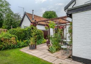 um jardim com uma pérgola e algumas plantas em Pike Cottage em Kettleburgh