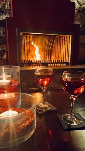 a table with two glasses of wine and a fireplace at Giagia Evgenia in Vitsa