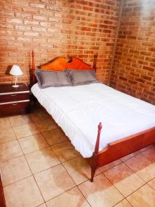 uma cama num quarto com uma parede de tijolos em Complejo Hatun Yaya em Mendoza