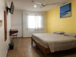 1 dormitorio con cama, ventana y escritorio en International House en Playa del Carmen