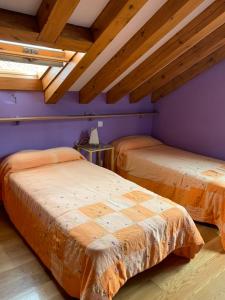 2 bedden in een kamer met paarse muren en houten plafonds bij Alojamiento Turístico Prellezo in Prellezo