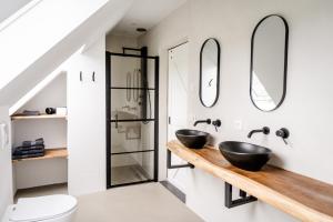 a bathroom with two sinks and two mirrors at Het Landzicht in Houtigehage +80 photos