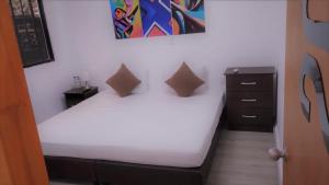 a small bedroom with a white bed and a dresser at Hotel BLH 2 in Bucaramanga