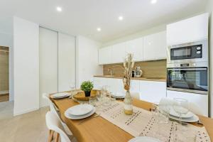 a kitchen with a wooden table and white cabinets at Le Rivera - Clim - Parking - Netflix - Nestor & Margot in Auterive +23 photos