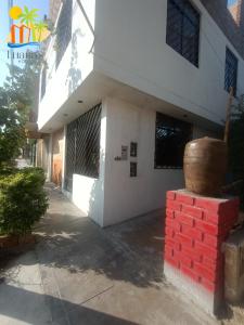 a white building with a red brick wall next to it at LUANA’S HOUSE in Ica