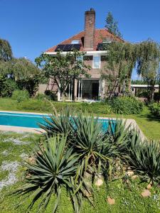 a house with a swimming pool in front of it at Ecolodge prive sauna, prachtige tuin, jacuzzi en warm zwembad in Tilburg