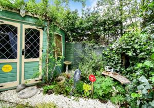 een tuin met een groen huis en een hek bij Cosy Garden Flat, Private Roofed Hot Tub & Four Poster Bed in York
