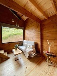 Habitación con sofá en una habitación de madera con ventana en Mountain Eco Shelter 9 en Funchal