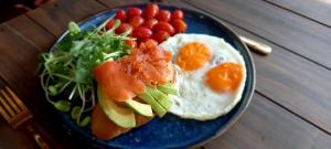 a blue plate of breakfast food with eggs and fruit at Paapu House in Chiang Mai