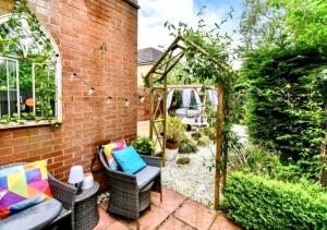 a patio with wicker chairs and a pergola at Cosy Garden Flat, Private Roofed Hot Tub & Four Poster Bed in York