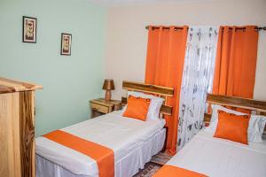 two beds in a room with orange curtains at The Hamilton's Nature Villa in Clarks Town