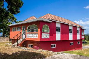 a red and white building with a staircase at The Hamilton's Nature Villa in Clarks Town