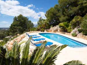 una piscina con tumbonas azules y árboles en Villa BLANCA en Altea