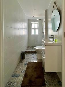 a bathroom with a sink and a toilet and a mirror at Pine House - Faro Airport, Beach and City Center in Faro