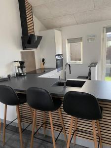 a kitchen with three black chairs and a counter at Fin ny moderniseret lejlighed i Skagen. in Skagen