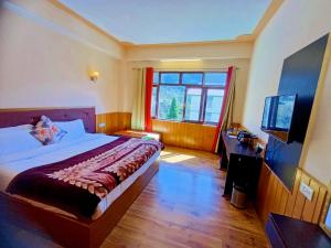 a bedroom with a bed and a desk and a television at Le Coxy Resort Lachung in Lachung