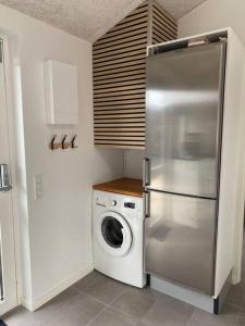 a kitchen with a refrigerator and a washing machine at Fin ny moderniseret lejlighed i Skagen. in Skagen