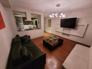 sala de estar con sofá negro y TV en Hotel Santa Rosa en Olavarría