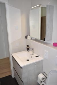 a white bathroom with a sink and a mirror at LAWSON'S GOLD BELL STUDIO in Luxembourg