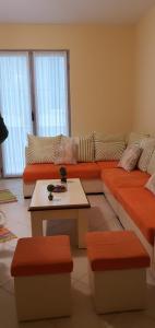 ein Wohnzimmer mit einem orangenen Sofa und einem Tisch in der Unterkunft Apartamenti 204 in Shëngjin