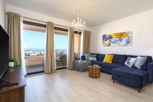 uma sala de estar com um sofá azul e uma grande janela em -MalagaSunApts-SkyGarden Teatinos Pool Playground em Málaga
