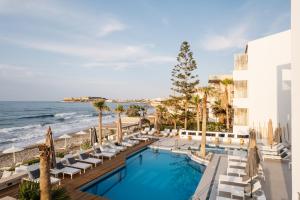 レティムノ・タウンにあるPetradi Beach Lounge Hotelのリゾートのプールとビーチの景色を望めます。