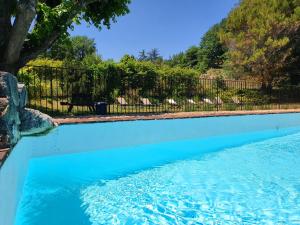 a swimming pool with blue water in a yard at Les Logis de Paban in Crestet