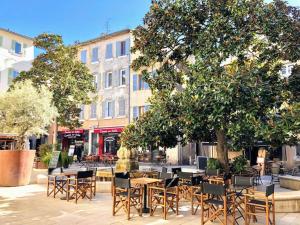 un patio con mesas y sillas bajo un árbol en Cosy d'Azur T2 centre historique-vieux port, en La Ciotat