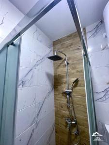 a shower in a bathroom with marble walls at J&S Apartments - Gornja Toponica in Gornja Toponica