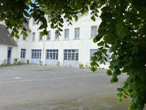 Un grand bâtiment blanc avec de nombreuses fenêtres dans l'établissement Demeure de kergoguen, à Plougonver