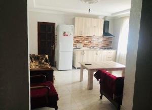 uma cozinha com uma mesa e um frigorífico branco em Villa Lizzy em Batumi