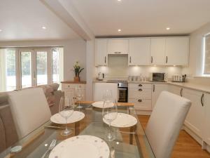 a kitchen with a glass table and white cabinets at The Winning Post in Bruton