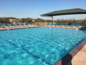 uma grande piscina com cadeiras azuis e um guarda-sol em Lake Travis Oasis, Walk to Pool, Gym, Marina, Food em Leander