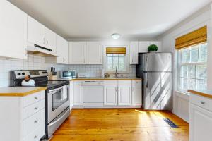 a kitchen with white cabinets and a stainless steel refrigerator at Little Loon Farm in Waldoboro