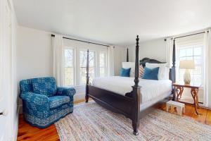 een slaapkamer met een bed en een blauwe stoel bij Little Loon Farm in Waldoboro