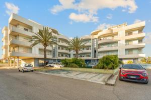 zwei Autos parkten vor einem großen Gebäude in der Unterkunft CagliariParadiseApartament Waves in Quartucciu