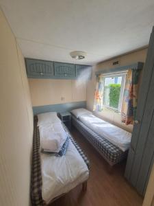 een kleine kamer met 2 bedden en een raam bij Camping Village Nature D'O in Hillion