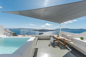 - un balcon avec une piscine, une table et des chaises dans l'établissement Thera Villas, à Fira 49 autres photos