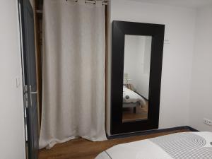 a mirror in a bedroom with a white curtain at bel appart T2 confortable en plein coeur de Sigean in Sigean +5 photos