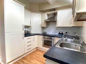 una cocina con armarios blancos y fregadero en Beautiful 2 bedroom apartment - close to beach, en Waterloo